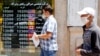 An Iranian man checks currency rates as he walks past an exchange bureau in Tehran. June 22, 2020. 