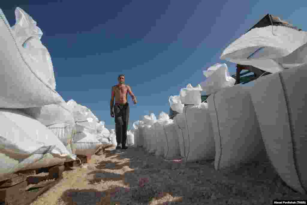 A worker walks alongside bags filled with salt. 