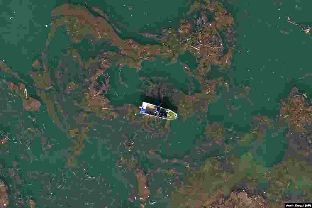 An aerial view shows a man rowing a boat through mud and waste after devastating floods and landslides polluted Jablanicko Lake near Ostrozac, Bosnia-Herzegovina.