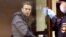 Russian opposition leader Aleksei Navalny, charged with defaming a World War II veteran, looks out from inside a glass cell during a court hearing in Moscow on February 5.