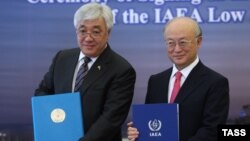 Kazakh Foreign Minister Erlan Idrisov (left) and Yukiya Amano, head of the IAEA, pose after signing an agreement to establish a bank of low-enriched uranium in Kazakhstan on August 27.