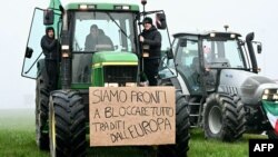 Итальянские фермеры паркуют свои тракторы вдоль дороги во время акции протеста возле въезда на шоссе в Меленьяно, недалеко от Милана, 30 января 2023 года