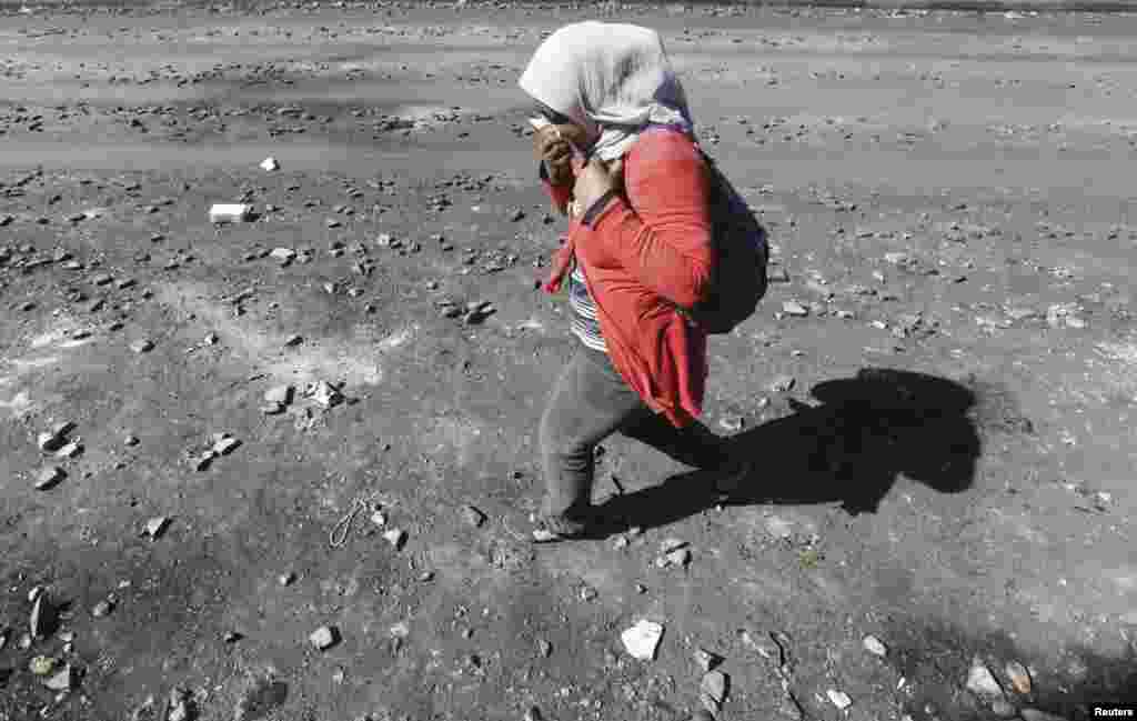 A woman shields her nose from tear gas along a road littered with stones and tear-gas canisters after clashes between riot policemen and protesters on Qasr el-Nil bridge, which leads to Tahrir Square, in Cairo. (Reuters/Amr Abdallah Dalsh)