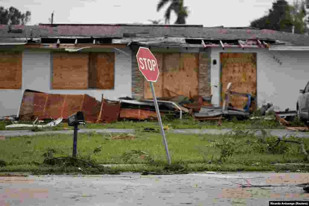 Fâșii de acoperiș zac în fața unei case. Proprietarii au blocat ferestreșe cu scânduri, să le protejeze de vântul puternic. Fort Myers, Florida, SUA, 9 octombrie 2024. Aproximativ 125 de case au fost distruse înainte ca uraganul să lovească țărmul.