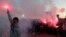 Opposition protesters hold up flares at the main entrance road of Tirana on May 2, 2019