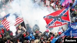 Bačen suzavac na demonstranate, od kojih jedan nosi zastavu Konfederacije sa porukom "Dođi i uzmi", tokom sukoba sa policijom Kapitola na skupu kojim se osporavalo potvrđivanje rezultata američkih predsjedničkih izbora 2020. godine, Washington (6. januar 2021.)