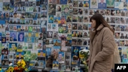 O femeie aduce flori la Zidul Comemorării celor Căzuți pentru Ucraina