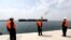 Workers watch a ship as it sails during an inauguration ceremony of new equipment and infrastructure at Shahid Beheshti Port in the southeastern Iranian coastal city of Chabahar, on the Gulf of Oman, on February 25, 2019.