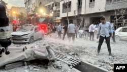 حضور مردم و نیروهای آتش‌نشانی در بیرون از ساختمانی که روز اول جنگ ایران و اسرائیل در تهران هدف قرار گرفت