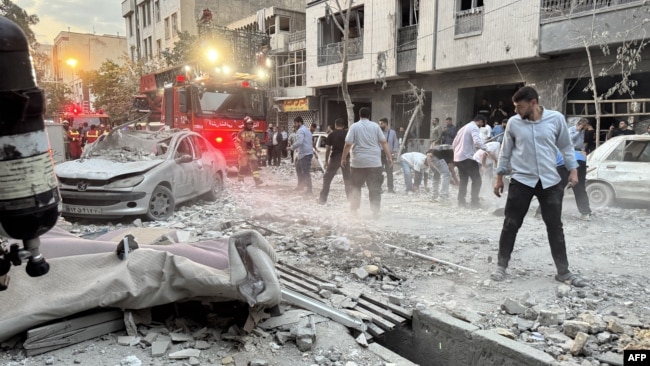 حضور مردم و نیروهای آتشنشانی در بیرون از ساختمانی که روز اول جنگ ایران و اسرائیل در تهران هدف قرار گرفت