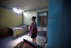 В азербайджанському селі Дондар Гущу жінка оглядає пошкодження її будинку, заподіяні вірменським снарядом