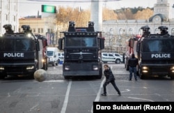 Хлопчик грає на тлі поліцейських вантажівок під час протестів і виборів нового президента, Тбілісі, 14 грудня 2024 року