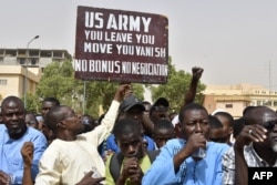 Muškarac drži transparent kojim se traži da američki vojnici napuste Niger, tokom demonstracija u Niameyu, 13. aprila 2024.