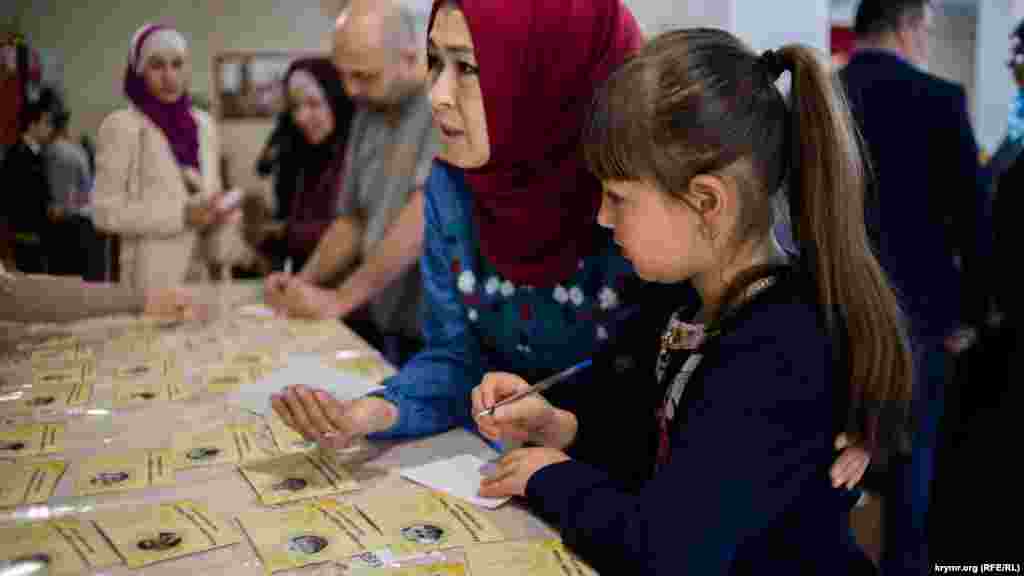 Körüşüv iştirakçileri tutulğan qırımtatarlar ve siyasiy mabüslerniñ süretlerinen otkrıtkalarnı imzalay