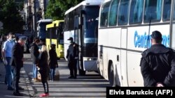 Migrants carry their belongings as they board buses during the evacuation of a makeshift camp in a park across from the City Hall in Sarajevo on May 18. 