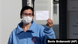Një infermiere tregon kartën e saj të vaksinimit pasi ka marrë një dozë të vaksinës Pfizer-BioNTech në Shkup, 17 Shkurt 2021.