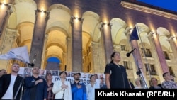 პარლამენტის წინ დამონტაჟებულ სცენაზე საქართველოს ჰიმნს უსმენენ