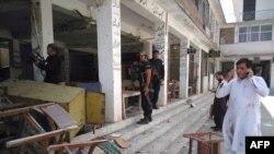 Pakistani police officials inspect the site of a suicide bomb attack at a district court in Mardan on September 2.