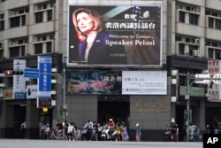 Люди проходят мимо рекламного щита, приветствующего спикера Палаты представителей США Нэнси Пелоси, в Тайбэе. Тайвань, 3 августа 2022 года