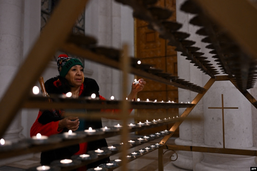 Një grua duke kryer lutje dhe duke ndezur një qiri në Katedralen në Prishtinë.