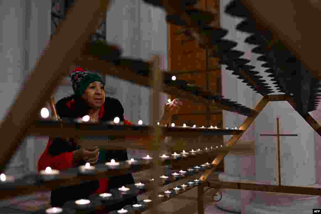 Një grua duke kryer lutje dhe duke ndezur një qiri në Katedralen në Prishtinë.