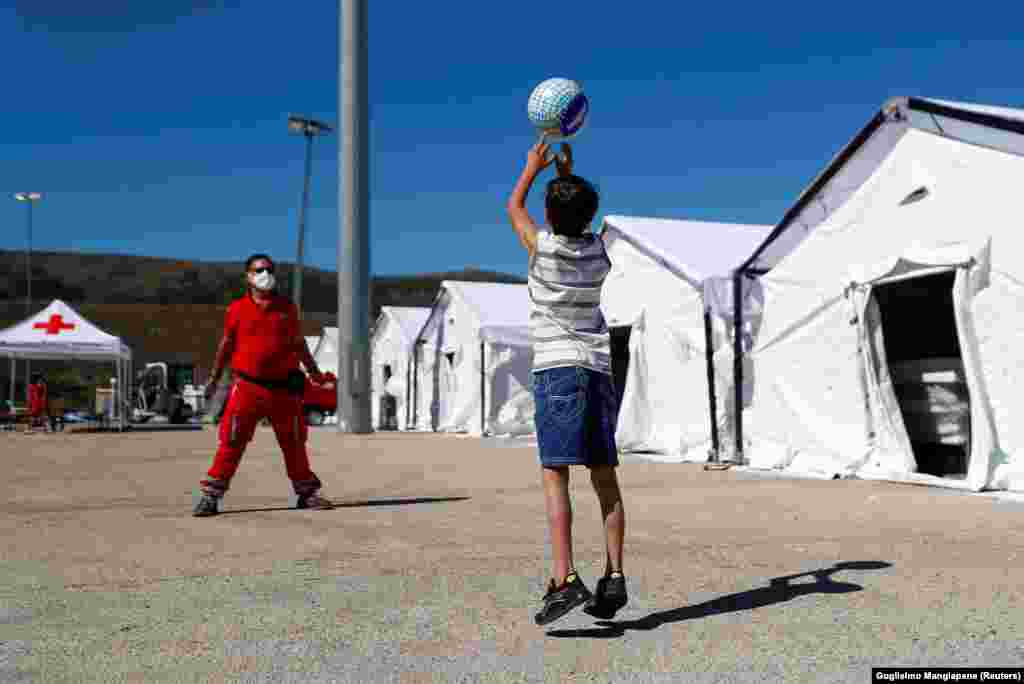 Un copil afgan se joacă cu mingea cu un membru al Crucii Roșii italiene, în centrul din Avezzano, Italia. &nbsp;