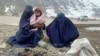 Gulnaz (left) tries to keep her 18-month-old son warm as they wait for alms next to the Kabul-Pul-e Alam highway in eastern Afghanistan.