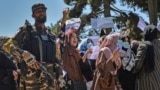 AFGHANISTAN -- A Taliban fighter stands guard as Afghan women shout slogans during an anti-Pakistan protest rally, near the Pakistan embassy in Kabul, September 7, 2021