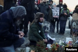  Жена седи пред спонтанния мемориал на мястото, където Алекс Прети беше убит в събота, 24 януари 2026 година 