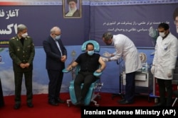 A son of slain scientist Mohsen Fakhrizadeh receives a Fakhra coronavirus vaccine as Defense Minister Gen. Amir Hatami (left) and Health Minister Saeed Namaki (2nd left) look on at a staged event in Tehran on March 16.