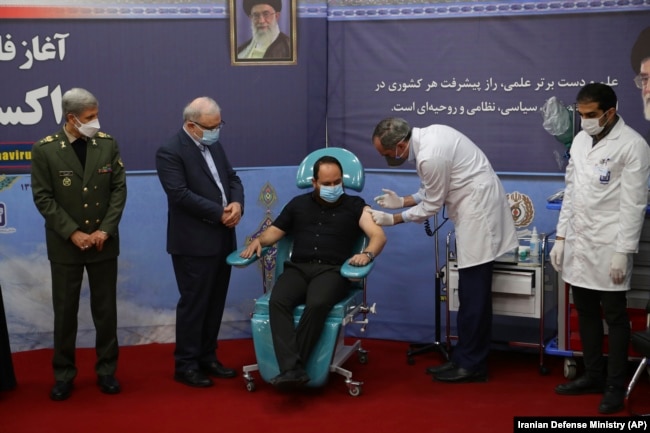 A son of slain scientist Mohsen Fakhrizadeh receives a Fakhra coronavirus vaccine as Defense Minister Amir Hatami (left) and Health Minister Saeed Namaki (second left) look on at a staged event in Tehran in March.