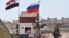 SYRIA -- A Russian soldier places the Russian national flag at the Abu Duhur crossing on the eastern edge of Idlib province, September 25, 2018