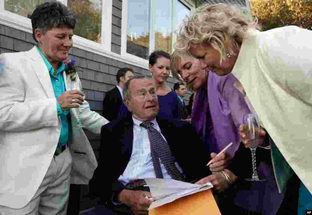 Former President George H.W. Bush (seated center) prepares to sign the marriage license of longtime friends Helen Thorgalsen (right) and Bonnie Clement (left) in Kennebunkport, Maine. Bush was an official witness at the same-sex wedding, his spokesman said. (AP/Susan Biddle)