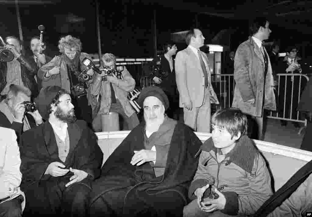 Khomeini talks briefly with reporters at Charles de Gaulle Airport in Paris, January 31, 1979, minutes before boarding a chartered airplane which was to fly him back to Iran after 14 years exile. His grandson is seen at his side.&nbsp;