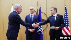 Finnish Foreign Minister Pekka Haavisto (left) shakes hands with U.S. Secretary of State Antony Blinken as NATO Secretary-General Jens Stoltenberg looks on during an accession ceremony at a NATO foreign ministers' meeting in Brussels on April 4. 