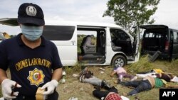 A police investigator gathers evidence at the scene of the massacre in Ampatuan.