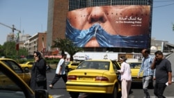 People walk past an anti-US billboard depicting US President Donald Trump and the Strait of Hormuz, in Tehran on May 11. 