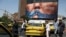 People walk past an anti-US billboard depicting US President Donald Trump and the Strait of Hormuz, in Tehran on May 11. 