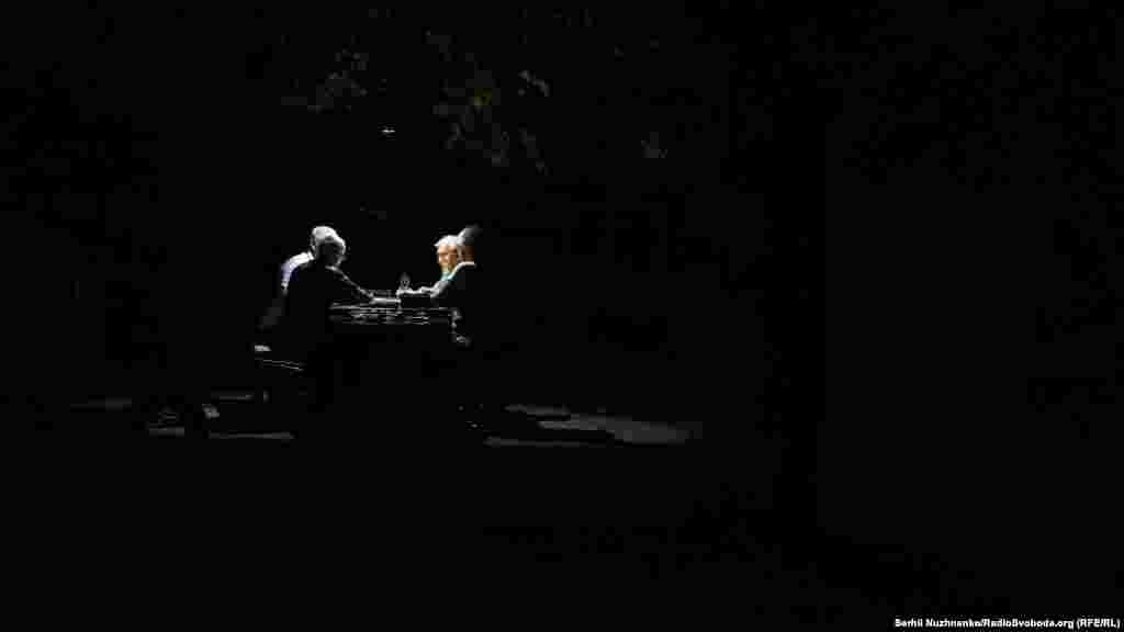 Чоловіки грають у доміно при світлі ліхтарика