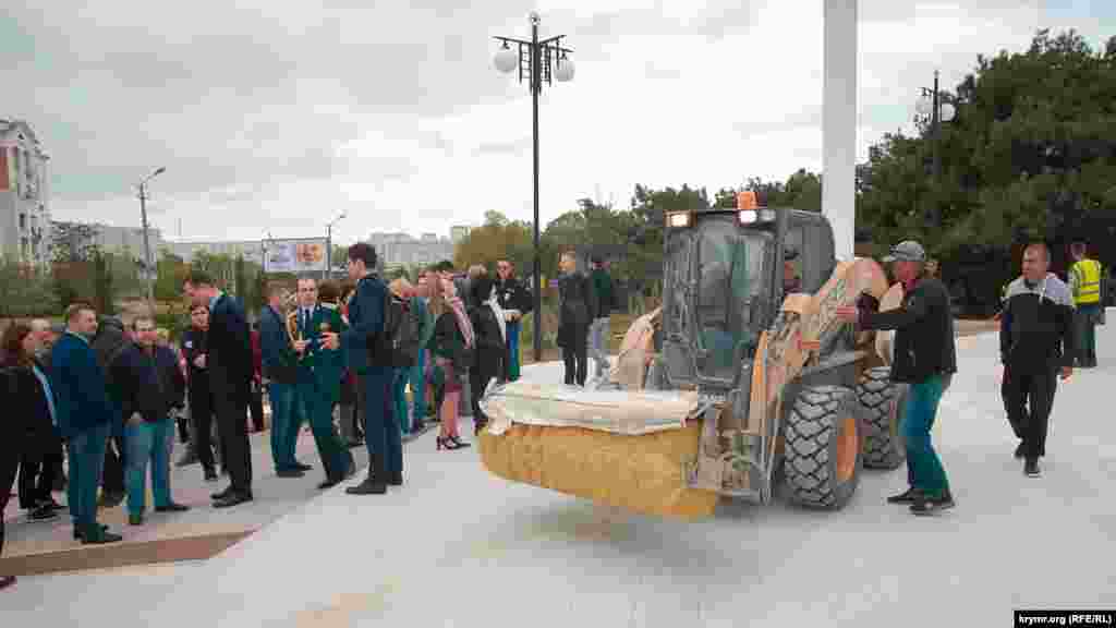 За кілька хвилин до приходу чиновників на подіум біля входу в парк пригнали трактор для прибирання від бруду та глини