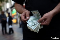 A currency dealer holds one-hundred-dollar bills in Tehran. (file photo)