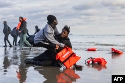 Нелегальные мигранты родом из Судана рыдают на берегу после того, как французские полицейские проткнули их надувную лодку, чтобы помешать им сесть на нее и пересечь Ла-Манш в направлении Великобритании. Пляж Гравлин вблизи Дюнкерка, север Франции, 26 апреля 2024 года