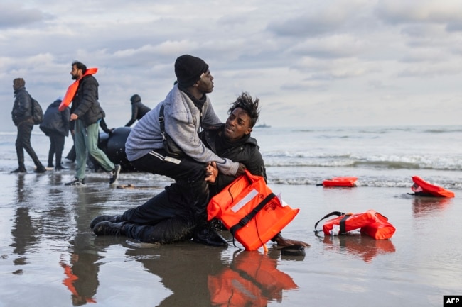 Нелегальные мигранты родом из Судана рыдают на берегу после того, как французские полицейские проткнули их надувную лодку, чтобы помешать им сесть на нее и пересечь Ла-Манш в направлении Великобритании. Пляж Гравлин вблизи Дюнкерка, север Франции, 26 апреля 2024 года