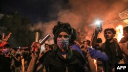 A protester wears tear gas canisters on his fingers and gestures the victory sign during anti-government protests in the Shiite shrine city of Karbala, south of Iraq's capital Baghdad, late on October 28, 2019.