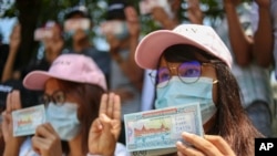 Tüntetők pénzre írt üzenetekkel egy ranguni tiltakozáson a katonai puccs ellen, Mianmarban, 2021. április 15-én
