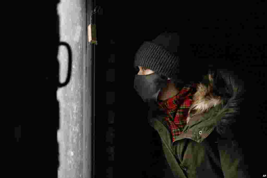 A young demonstrator looks out of a dark garage where he is hiding from the police during an opposition rally to protest the official presidential election results in Minsk on December 13. Crowds of people took to the streets of the Belarusian capital in a traditional weekly protest against the country&#39;s authoritarian leader Alyaksandr Lukashenka. (AP)