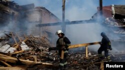 Ukrán tűzoltók egy lerombolt gyár romjai között a Donyecki területen 2022. augusztus 27-én