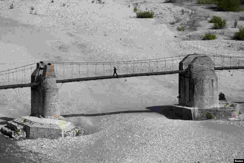 Një burrë duke ecur mbi një urë buzë luginës së lumit Vjosa, i shpallur rezervë e biosferës nga Organizata për Edukim, Shkencë dhe Kulturë e Kombeve të Bashkuara (UNESCO). Fotografi e 5 tetorit 2025. 