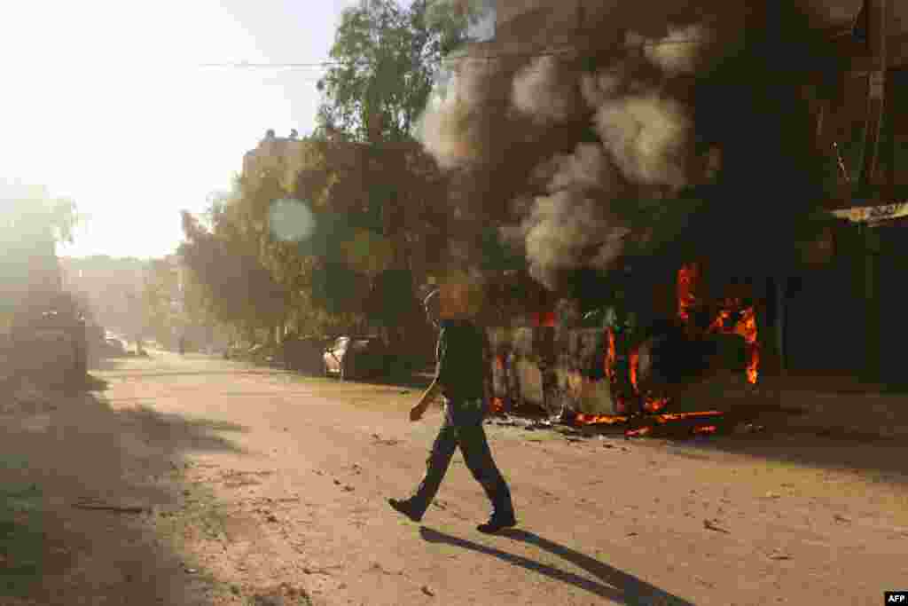 A Syrian man walks past a bus set ablaze following a reported air strike in the rebel-held Salaheddin district of Aleppo. (AFP/Ameer Alhalbi)