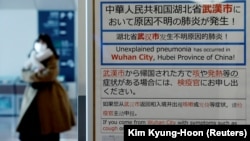 A woman wearing a mask walks past a quarantine notice about the outbreak of coronavirus in Wuhan, China at an arrival hall at a Tokyo airport.